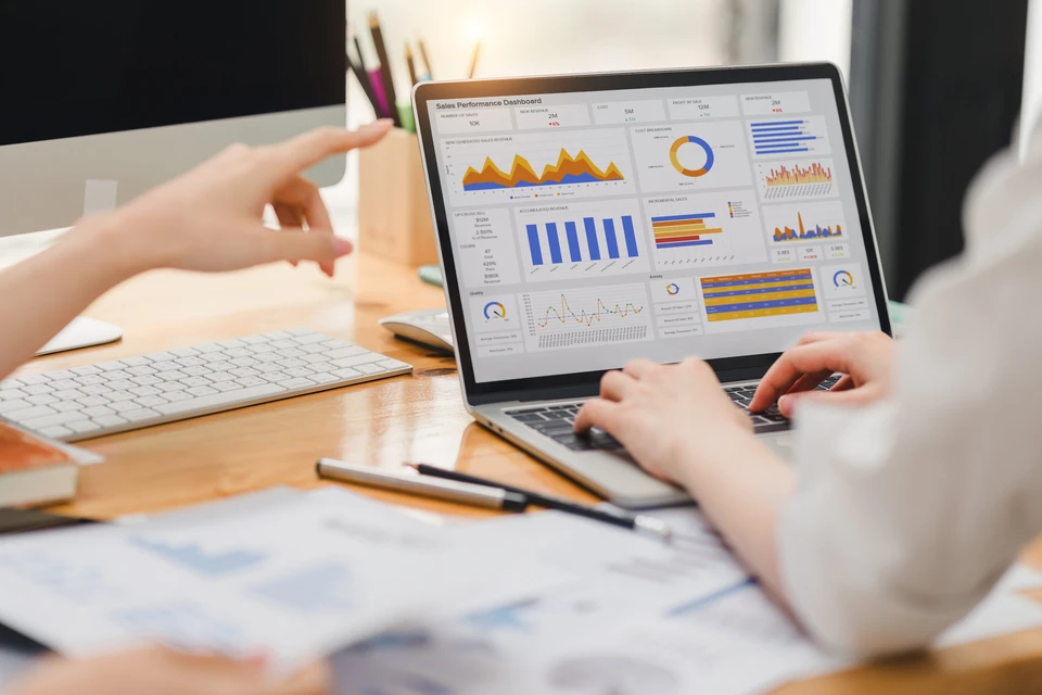 Personne travaillant sur ordinateur portable affichant tableau de bord analytique avec graphiques de performance commerciale