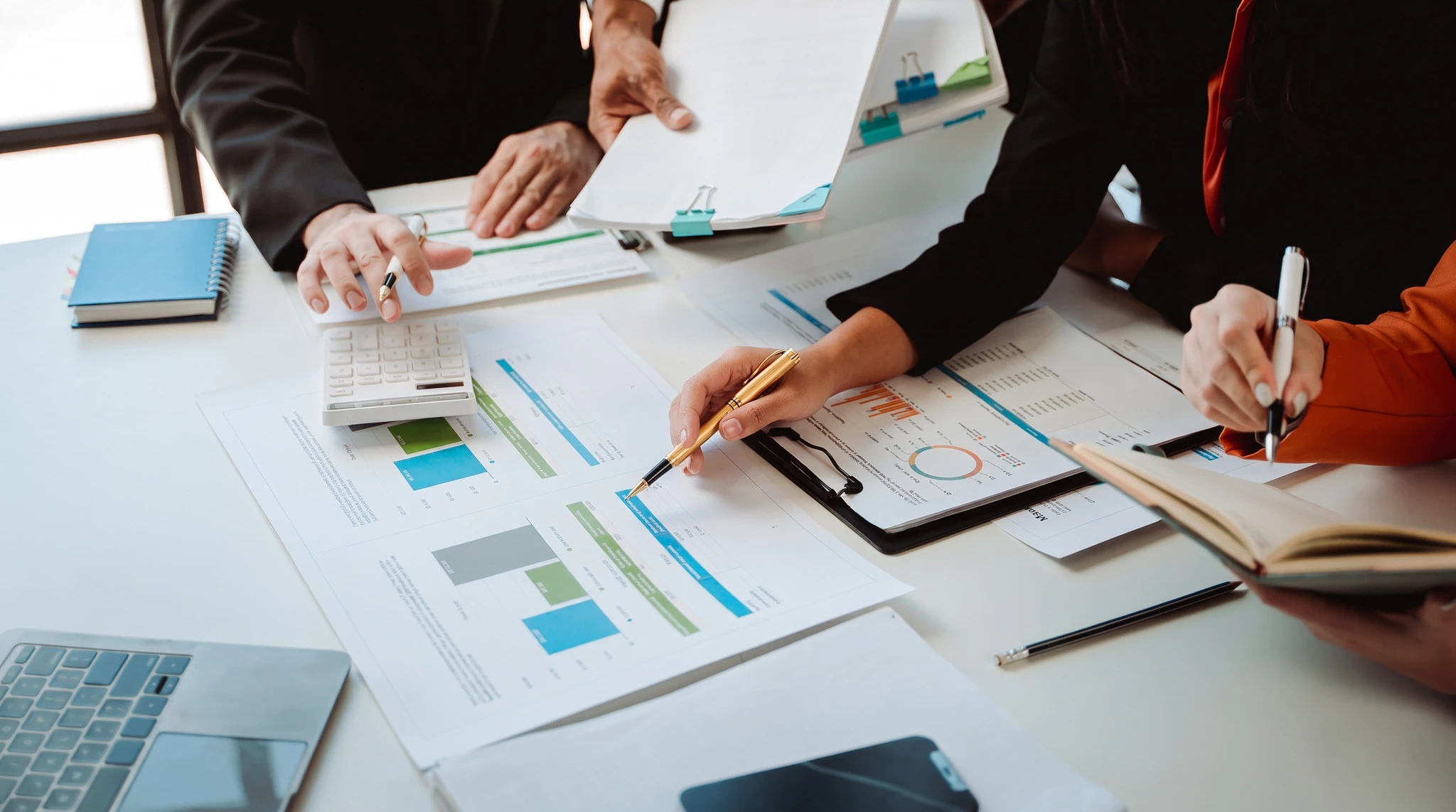 Réunion d'affaires autour d'une table en bois clair avec deux personnes analysant des documents contractuels et graphiques