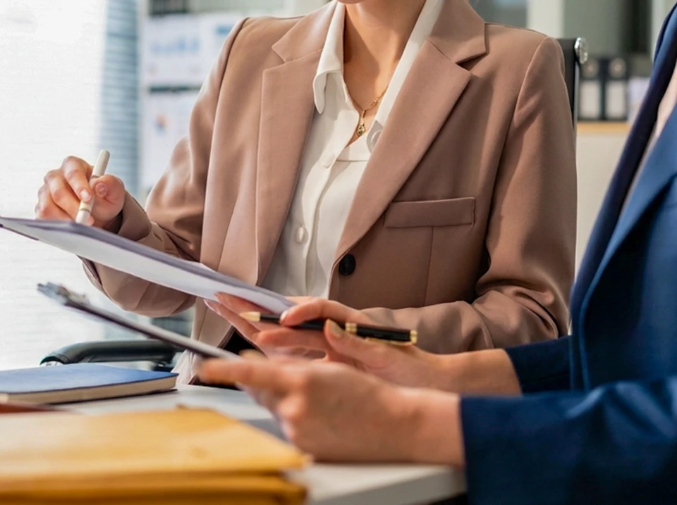 Réunion d'affaires dans un bureau moderne avec deux professionnels examinant des documents contractuels