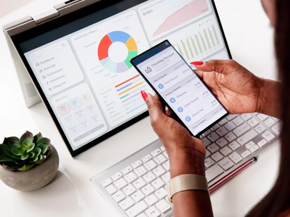 Personne travaillant sur ordinateur portable dans bureau moderne, analysant tableaux de bord financiers avec graphiques et métriques